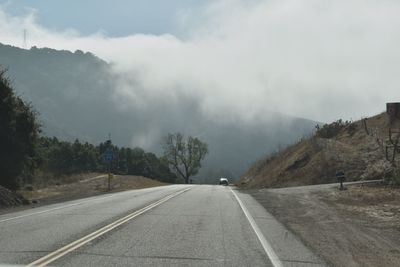 Road amidst trees against sky