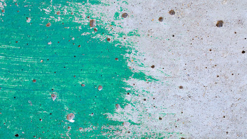 Close up shot of an unfinished green paint on plain concrete wall surface texture background