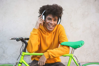 Portrait of smiling young man holding bicycle against wall