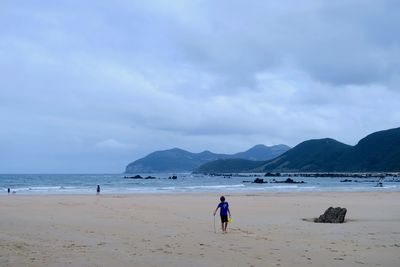 Rear view of man on beach against sky