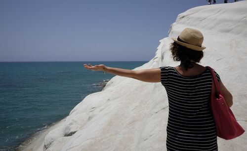 Rear view of woman standing by sea against clear sky