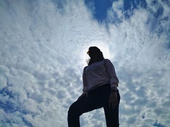 Low angle view of teenage girl standing against sky