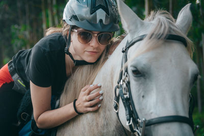 Woman wearing sunglasses and helmet riding horse 