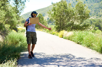 Man gesturing thumbs up while standing on road amidst plants