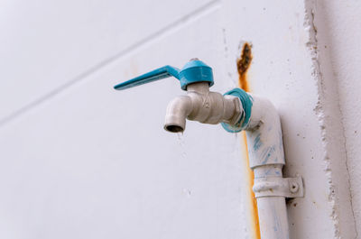 Close-up of faucet against white wall