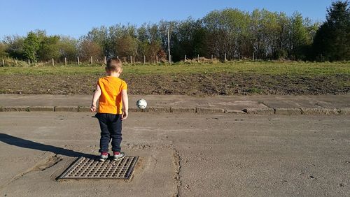 Rear view of boy playing on road