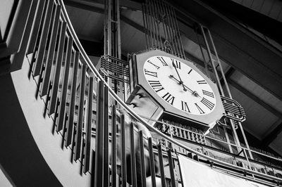 Low angle view of clock on railing against wall