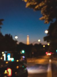 Defocused image of illuminated city street against sky at night