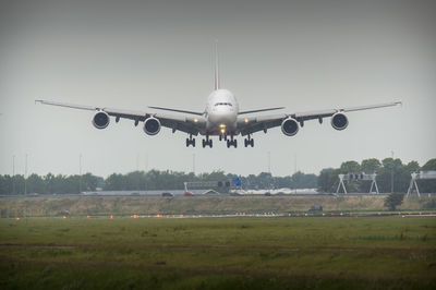 Airplane flying over field against sky