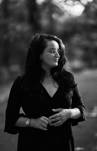 Portrait of young woman standing against trees