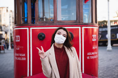 Portrait of woman wearing mask standing against cable car outdoors
