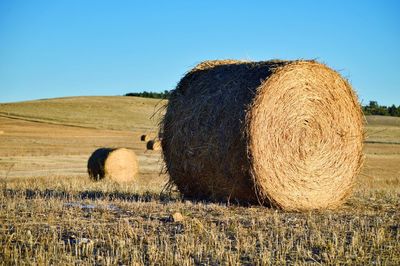 Hay bales on field against clear sky