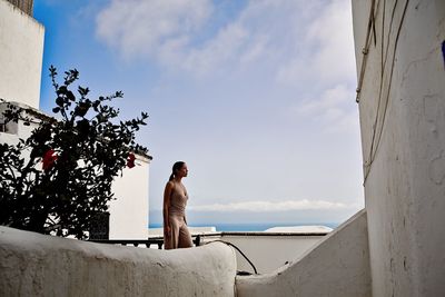 Man sitting by sea against sky