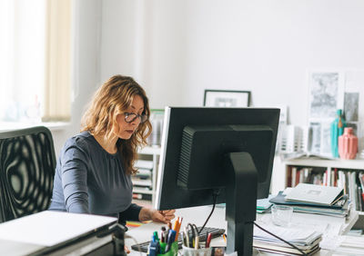 Charming woman middle aged woman with curly hair architect designer working on computer in office