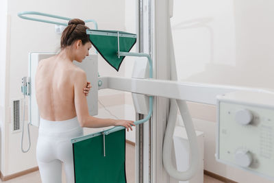 Rear view of woman standing in bathroom