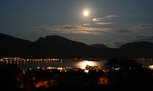 Silhouette mountain by lake against sky at night