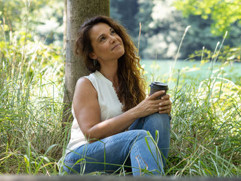 Mid adult woman using mobile phone while sitting on grass