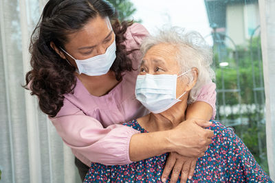 Caregiver help asian senior woman on wheelchair and wearing a face mask 