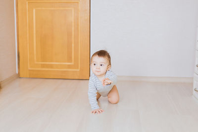 Portrait of cute girl sitting on wooden floor at home
