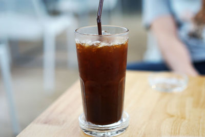 Close up glass of iced black coffee on wooden table