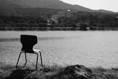Empty chair on shore by lake