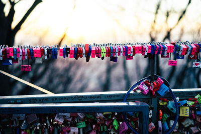 Colorful locks hanging on railing against sky