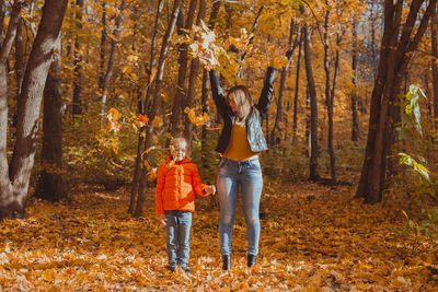 Mother and daughter in forest during autumn