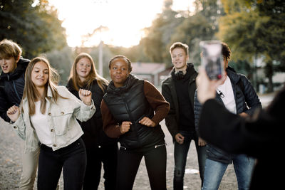 Woman filming teenage girls and boys dancing on street in city