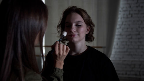 Portrait of young woman holding camera at home