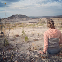 Rear view of woman sitting on land
