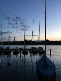 Boats moored at harbor against sky during sunset