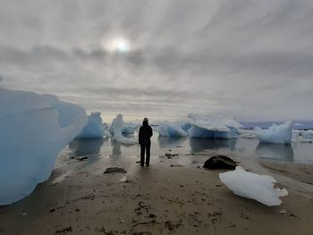 Rear view of people on beach against sky during winter