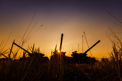 Close-up of silhouette grass on field against sky during sunset