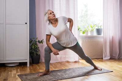 Side view of young woman exercising at home