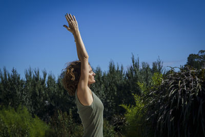 Rear view of woman with arms raised against clear sky