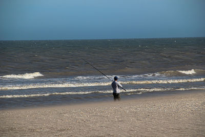 Fishermen on the beach. man standing on beach against clear sky