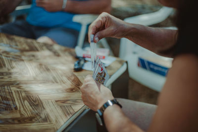 Midsection of friends playing cards