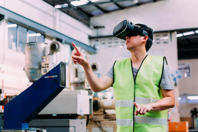 Man gesturing while wearing virtual reality simulator in factory