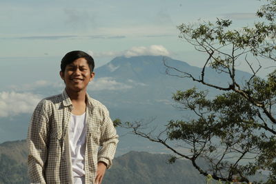 Young man standing on mountain against sky