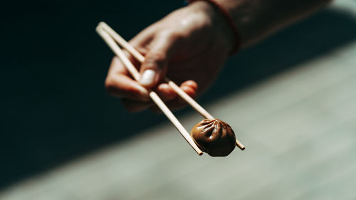 Cropped hand holding food against black background