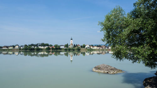 Scenic view of lake by building against blue sky