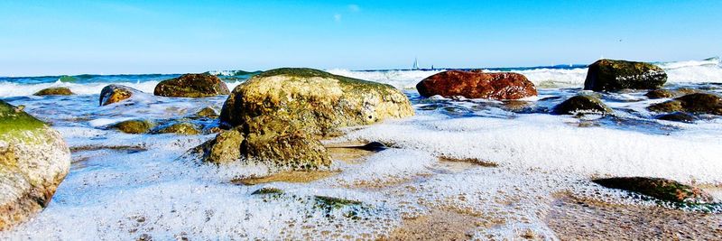 Rocks on shore during winter against sky