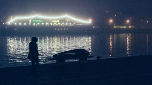 Rear view of silhouette man on water at night