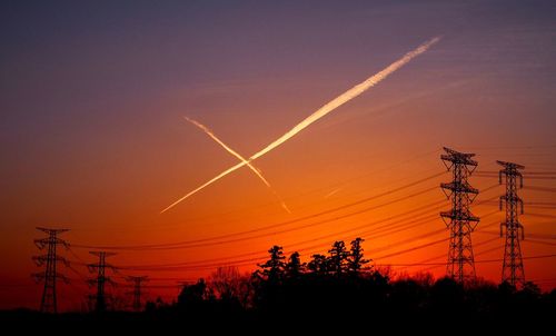 Silhouette of electricity pylon at sunset