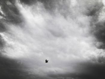 Low angle view of airplane flying against cloudy sky