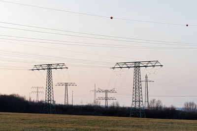 Low angle view of electricity pylon on field against sky