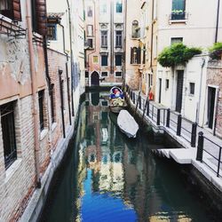 Boats moored in canal amidst buildings