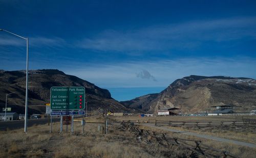 Road sign on field against mountains