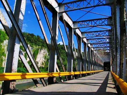 transportation, connection, bridge - man made structure, railing, the way forward, built structure, diminishing perspective, tree, bridge, vanishing point, architecture, sky, long, engineering, clear sky, blue, metal, day, sunlight, footbridge