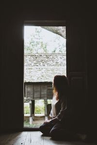 Woman looking through window at home